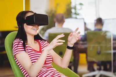 Happy young female executive enjoying augmented reality glasses at creative office