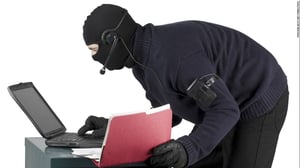 Maskted visitor stealing office data off a laptop computer