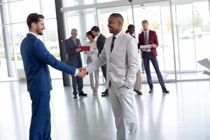Two business people greeting each other with a handshake in modern reception area