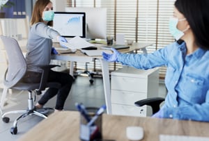 Office workers with gloves and masks share documents