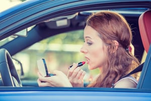 Woman applying makeup while driving a car