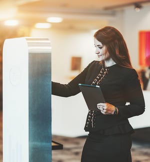 Business woman using visitor management kiosk to sign a legal document