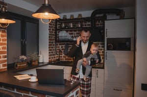 Tech employee works from home while holding a baby
