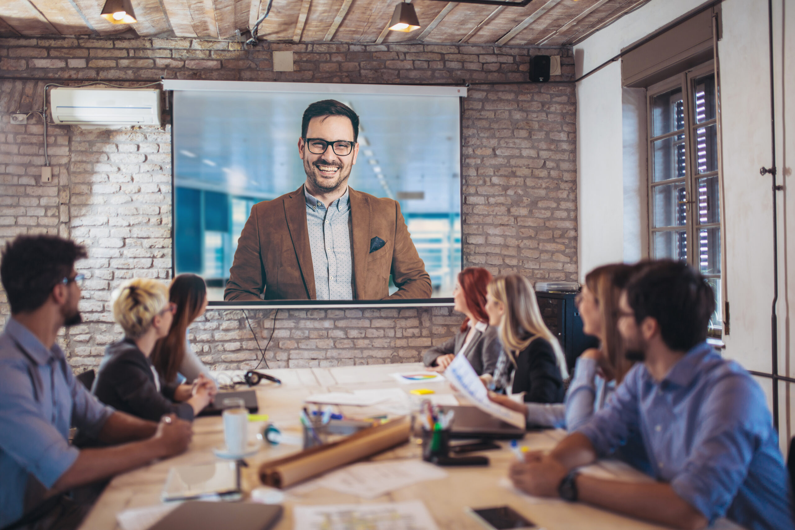 Business people looking at projector during video conference in office Business people looking at projector during video conference in office